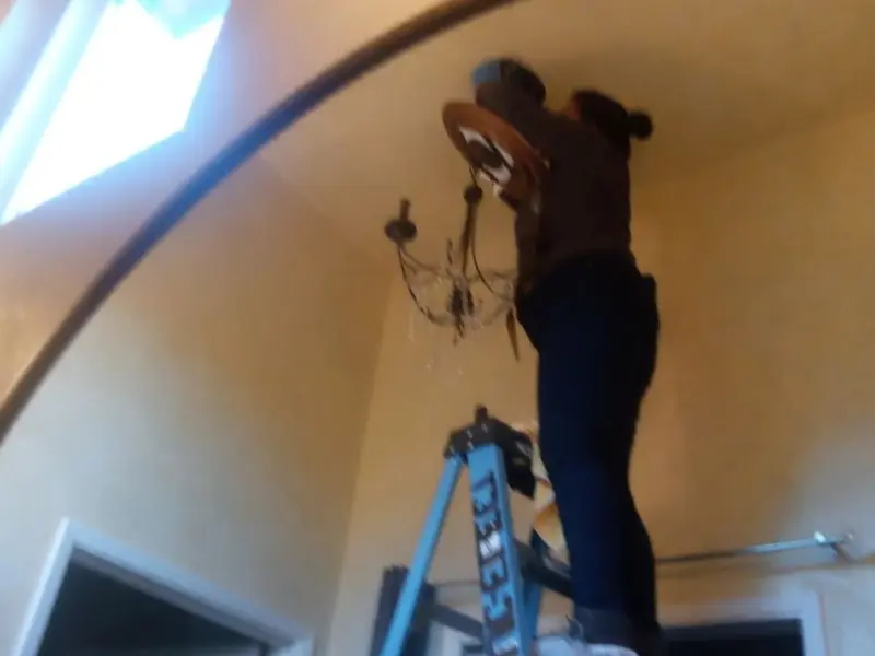 Electrician installing a chandelier in a French Island residence